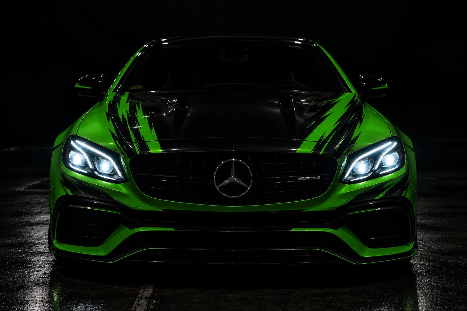 Green sports car with black graphics in the dark, headlights on
